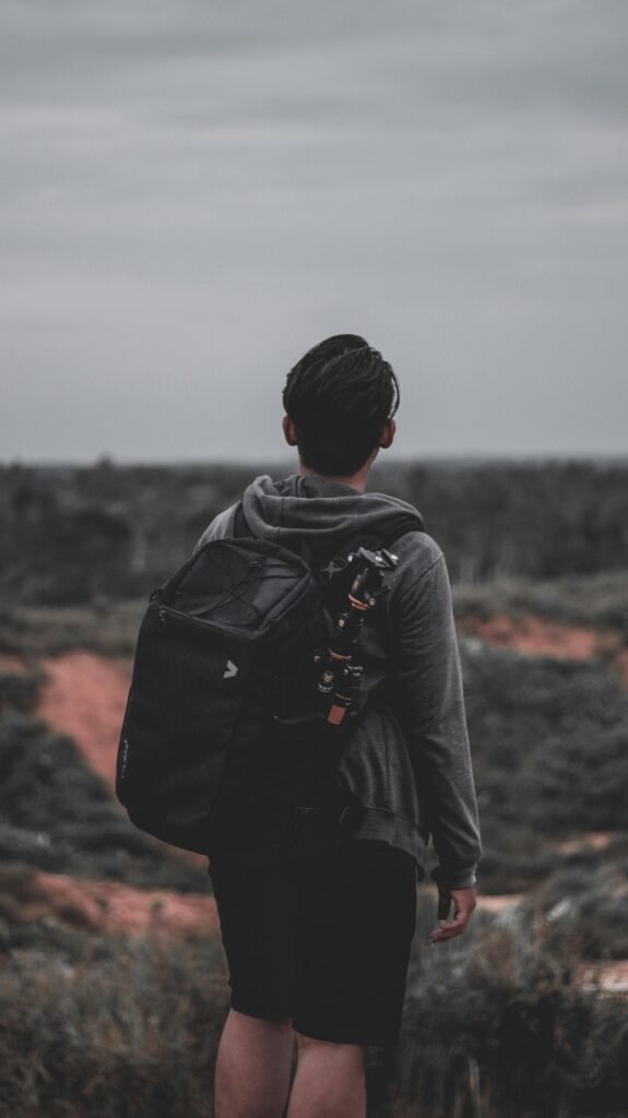 A young man with a backpack enjoys a quiet hike in a serene outdoor landscape.